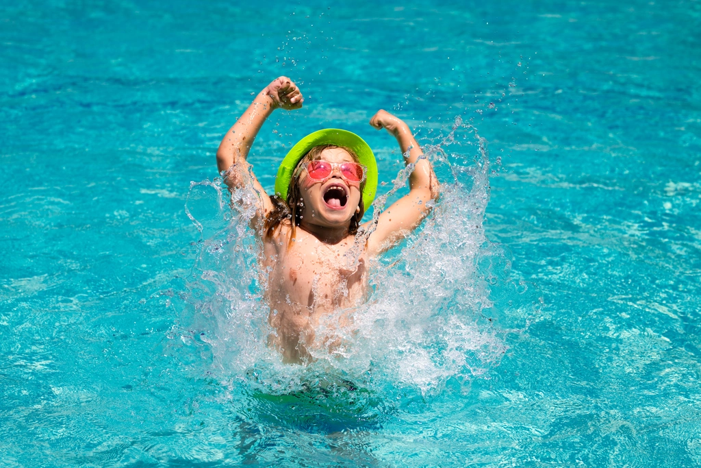 a child with a hat and glasses enjoys a dip in the La Chenaie pool