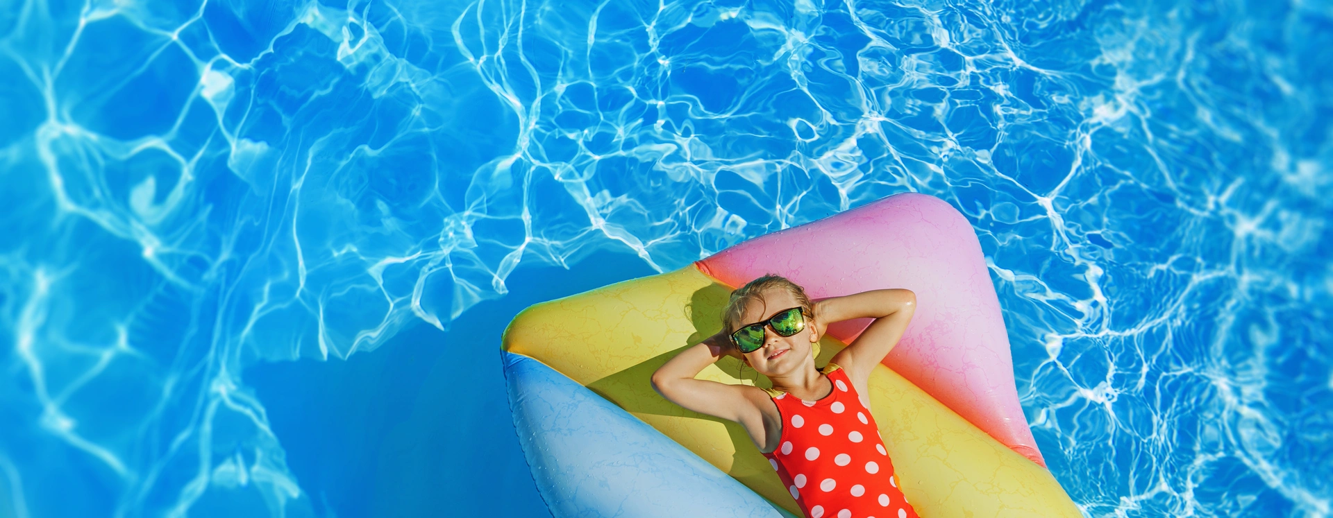 Kind auf einer Sonnenliege in der Mitte des Chenaie-Pools